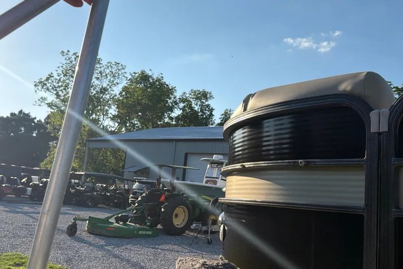 Slide: The Image of 2017 Manitou 25 Legacy pontoon boat near tractors and equipment under a clear sky. - 15