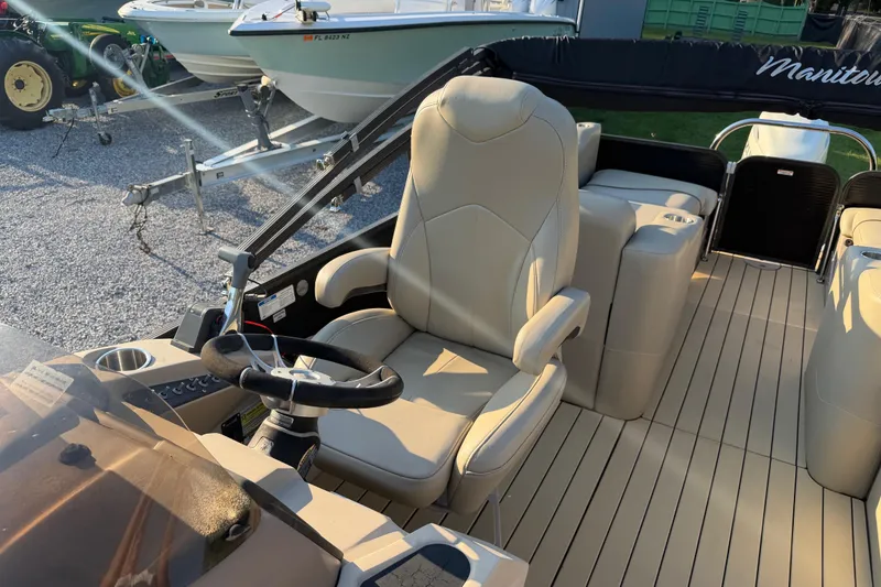 Slide: The Image of 2017 Manitou 25 Legacy boat interior with beige seating and steering wheel. - 17