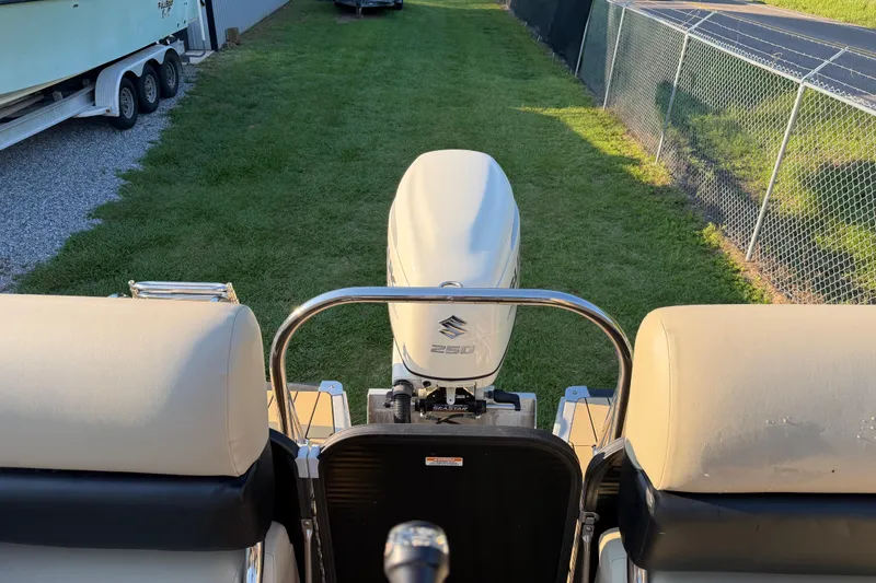 Slide: The Image of 2017 Manitou 25 Legacy boat with Suzuki 250 engine, parked on grass near a fence. - 20