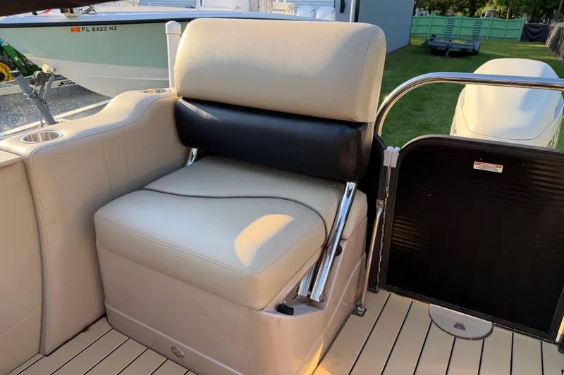 Slide: The Image of Luxurious seating on a 2017 Manitou 25 Legacy boat, featuring beige upholstery and cup holders. - 21
