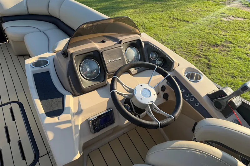 Slide: The Image of 2017 Manitou 25 Legacy boat dashboard with steering wheel and control panel. - 26