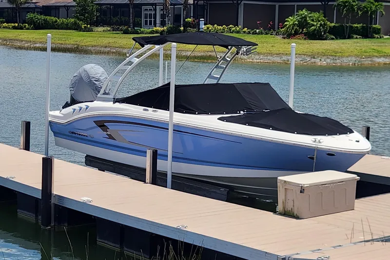 The Image of 2022 Chaparral 21 SSi OB boat docked on a serene lake with a black cover. - 1