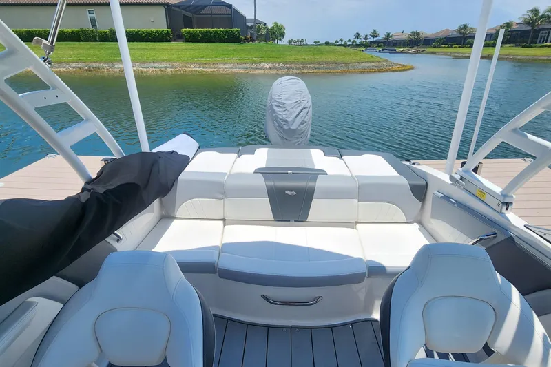 Slide: The Image of 2022 Chaparral 21 SSi OB boat interior with white seating, docked by a serene lake. - 13