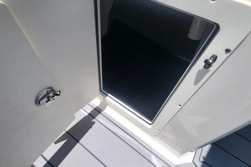 Slide: The Image of Open storage compartment on 2022 Chaparral 21 SSi OB boat, featuring secure latch. - 26