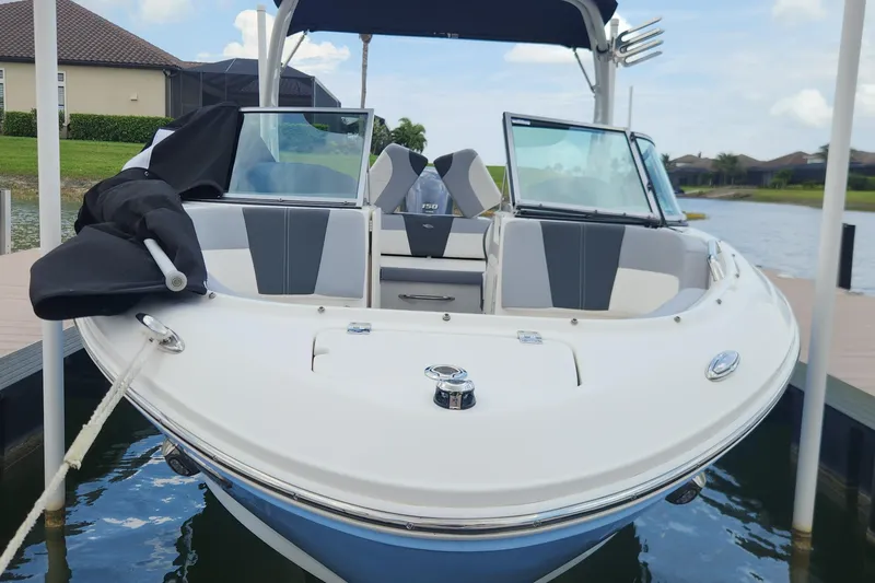 Slide: The Image of 2022 Chaparral 21 SSi OB boat docked, featuring sleek design and modern seating. - 58