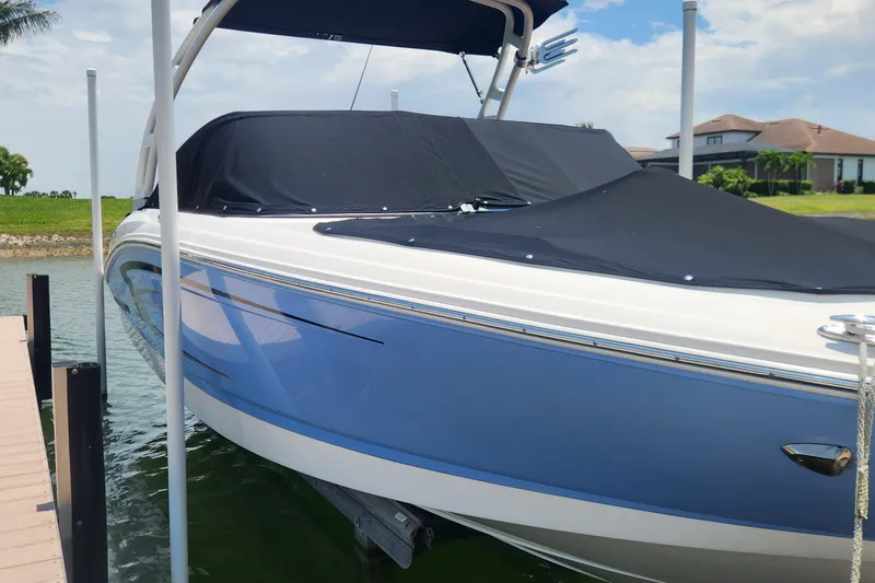 Slide: The Image of 2022 Chaparral 21 SSi OB boat with blue hull, docked and covered. - 6