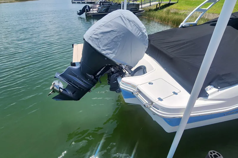 Slide: The Image of 2022 Chaparral 21 SSi OB boat with covered outboard motor docked on calm water. - 7