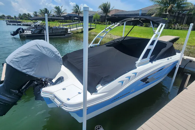 Slide: The Image of 2022 Chaparral 21 SSi OB boat docked, covered, with outboard motor, in a scenic marina. - 8