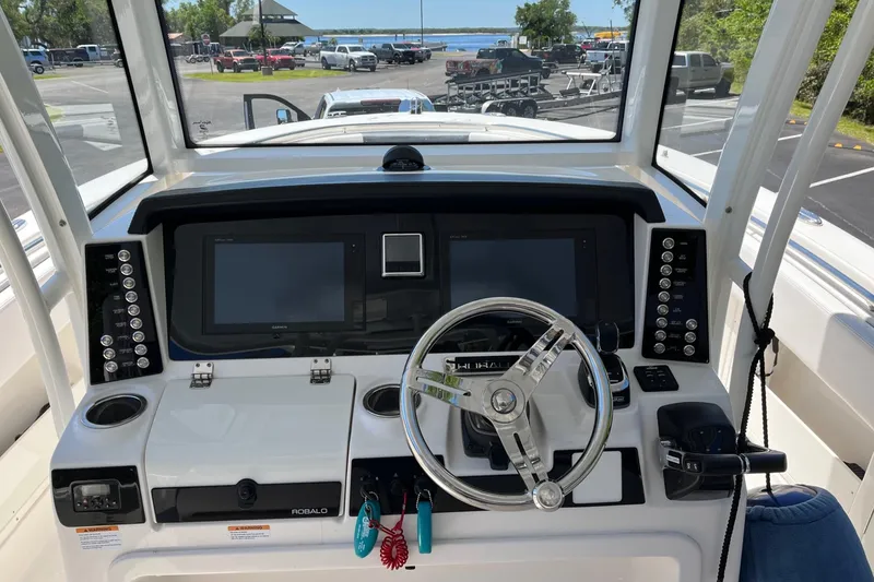 Slide: The Image of 2019 Robalo R302 Center Console boat dashboard with steering wheel and navigation screens. - 12