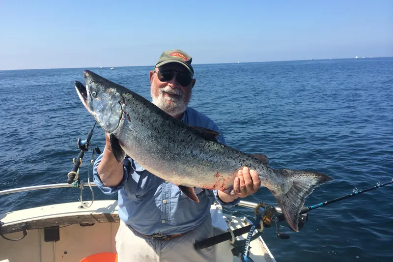 The Image of Man holding large fish on 1974 Dyer 29' Sport Fisher boat, ocean backdrop. - 0