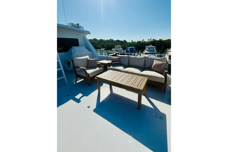 Slide: The Image of Outdoor seating area on 2001 Hargrave 94 yacht, featuring wooden furniture and scenic marina view. - 11