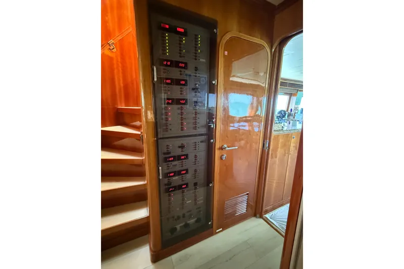 Slide: The Image of Electrical panel inside a 2001 Hargrave 94 yacht, featuring wooden interior and staircase. - 18