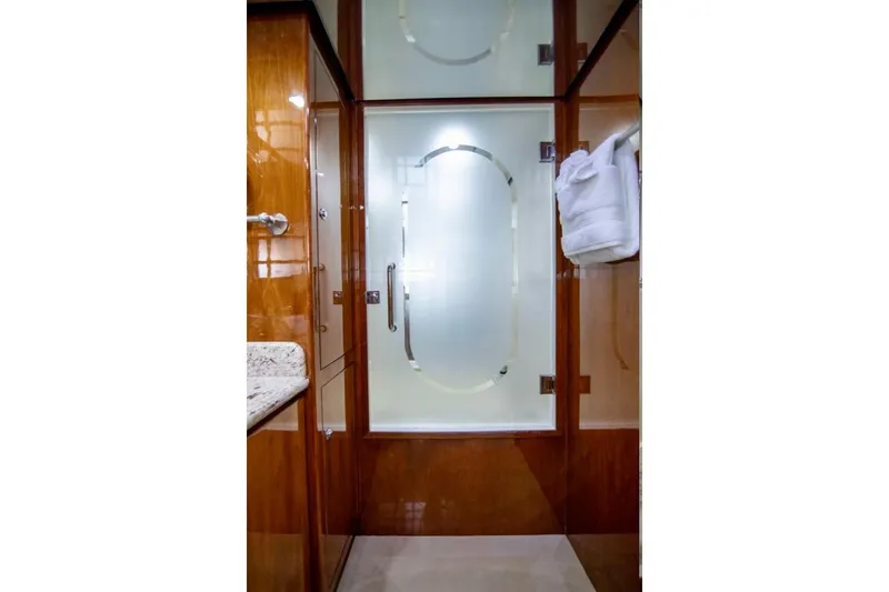 Slide: The Image of Luxurious bathroom interior on a 2001 Hargrave 94 yacht, featuring elegant wood finishes and frosted glass. - 67