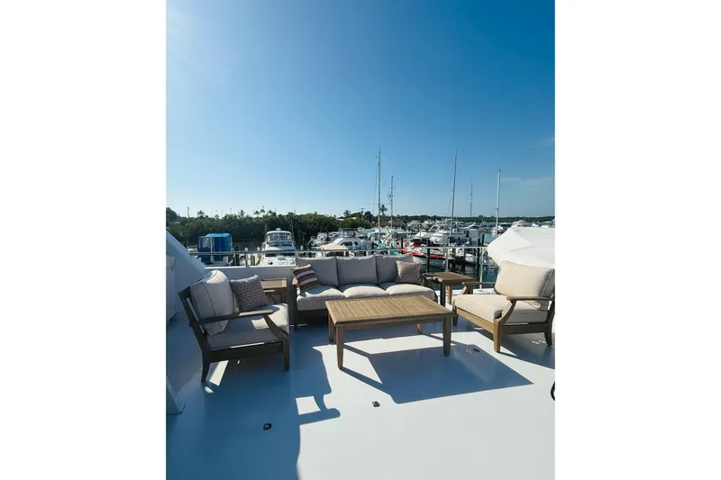 Slide: The Image of Luxurious outdoor seating on 2001 Hargrave 94 yacht, overlooking marina under clear blue sky. - 9