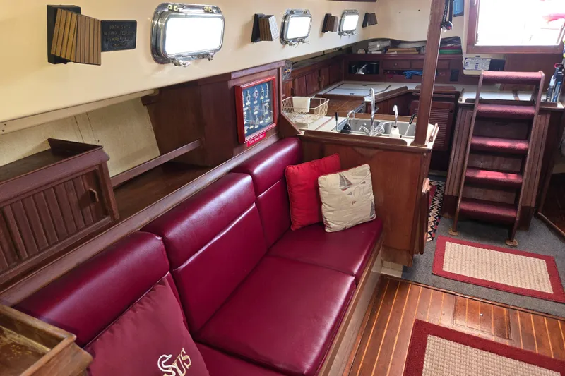 Slide: The Image of Interior of 1989 Island Packet 35 sailboat with red seating and wooden cabinetry. - 11