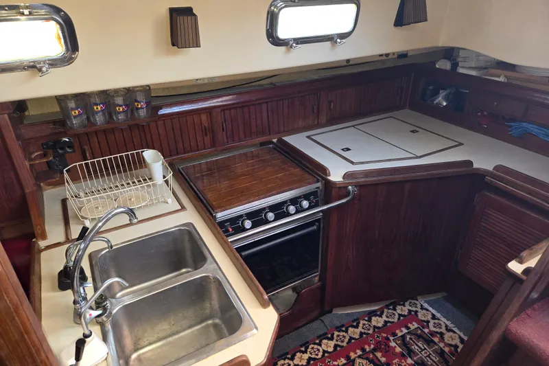 Slide: The Image of Interior of 1989 Island Packet 35 sailboat kitchen with sink, stove, and wooden cabinetry. - 12