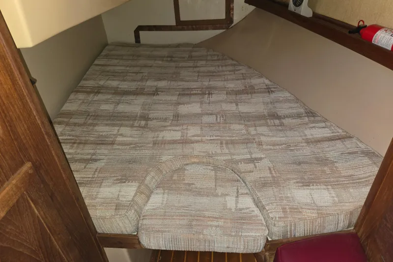 Slide: The Image of 1989 Island Packet 35 sailboat cabin with a patterned mattress and wooden interior. - 13