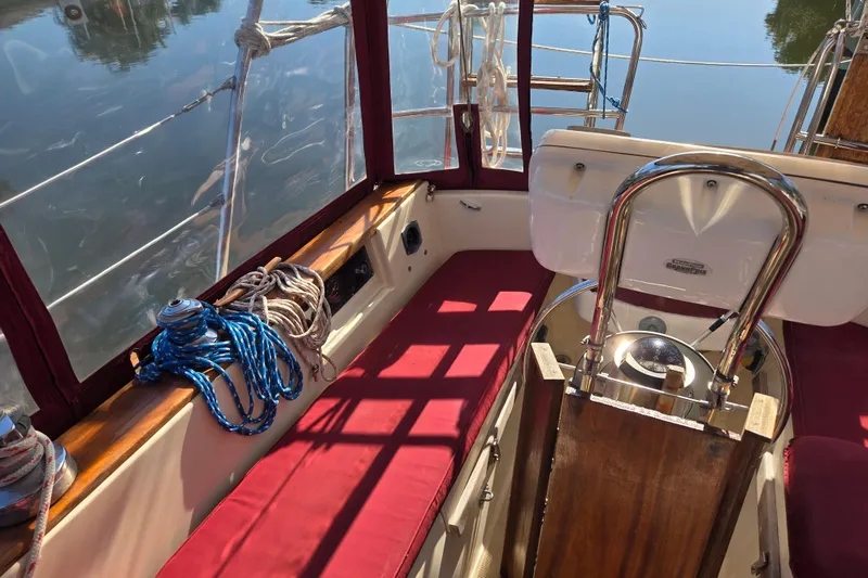 Slide: The Image of 1989 Island Packet 35 sailboat cockpit with red cushions and nautical ropes. - 14