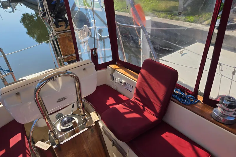 Slide: The Image of Cockpit of 1989 Island Packet 35 sailboat with red cushions and steering wheel. - 15