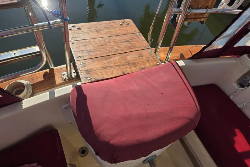 Slide: The Image of Cockpit of 1989 Island Packet 35 sailboat with red cushions and wooden deck. - 16