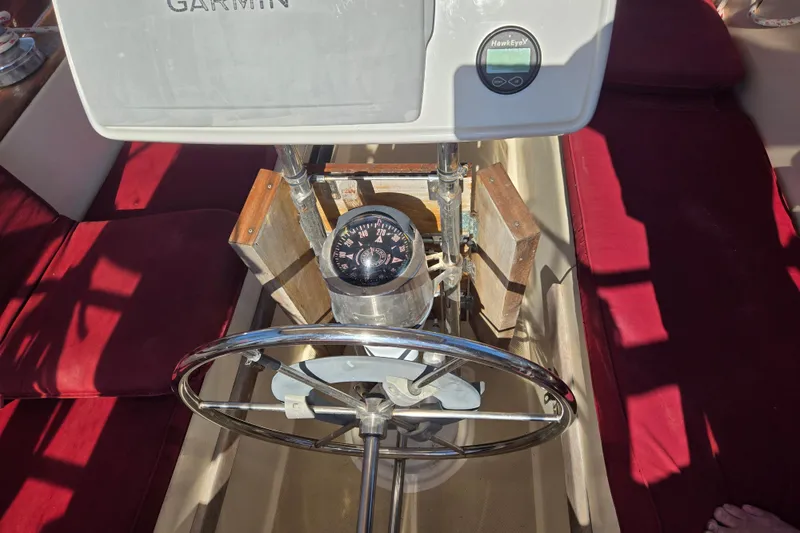 Slide: The Image of Steering wheel and compass on a 1989 Island Packet 35 sailboat with red seating. - 17