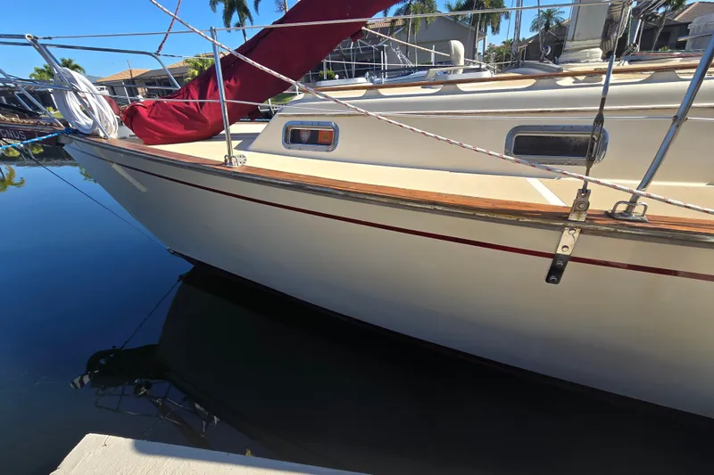 Slide: The Image of 1989 Island Packet 35 sailboat docked, featuring sleek design and vibrant red sail cover. - 2