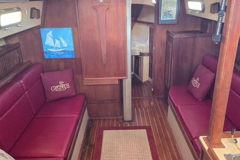 Slide: The Image of Interior of 1989 Island Packet 35 sailboat with red seating and wooden finishes. - 25