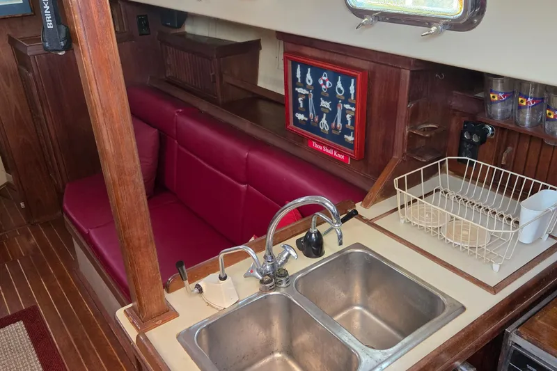 Slide: The Image of Interior of 1989 Island Packet 35 sailboat with red seating and kitchen sink area. - 26