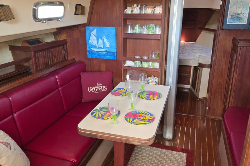 Slide: The Image of Interior of 1989 Island Packet 35 sailboat with red seating, dining table, and nautical decor. - 30