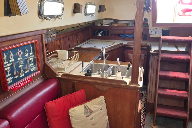 Slide: The Image of Interior of 1989 Island Packet 35 sailboat with wooden cabinetry and compact kitchen area. - 31