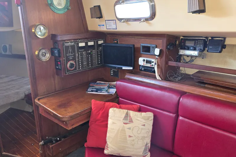 Slide: The Image of Interior of a 1989 Island Packet 35 sailboat with navigation equipment and red seating. - 32