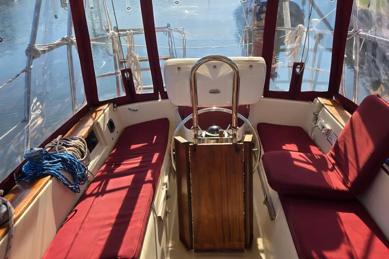Slide: The Image of Cockpit of 1989 Island Packet 35 sailboat with red cushions and steering wheel. - 4