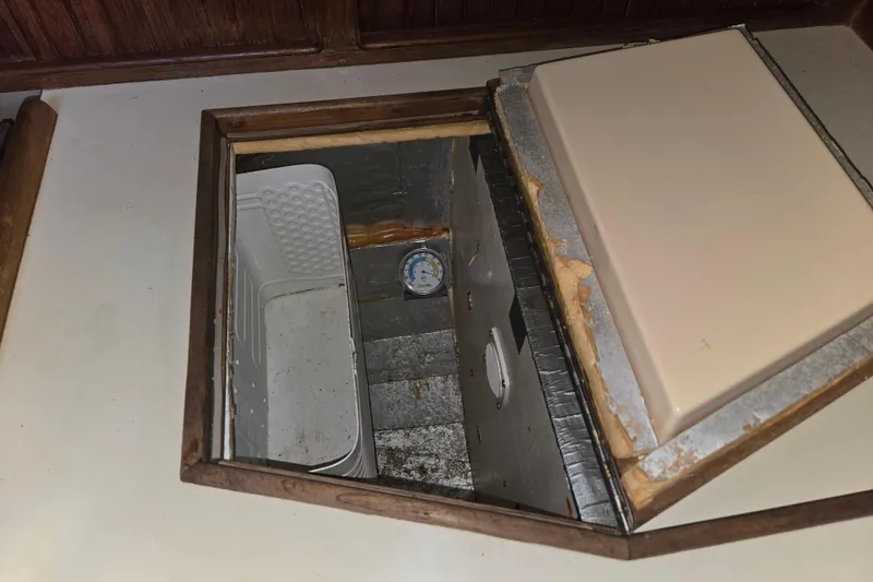 Slide: The Image of Open storage compartment on 1989 Island Packet 35 boat, featuring a thermometer and plastic container. - 42