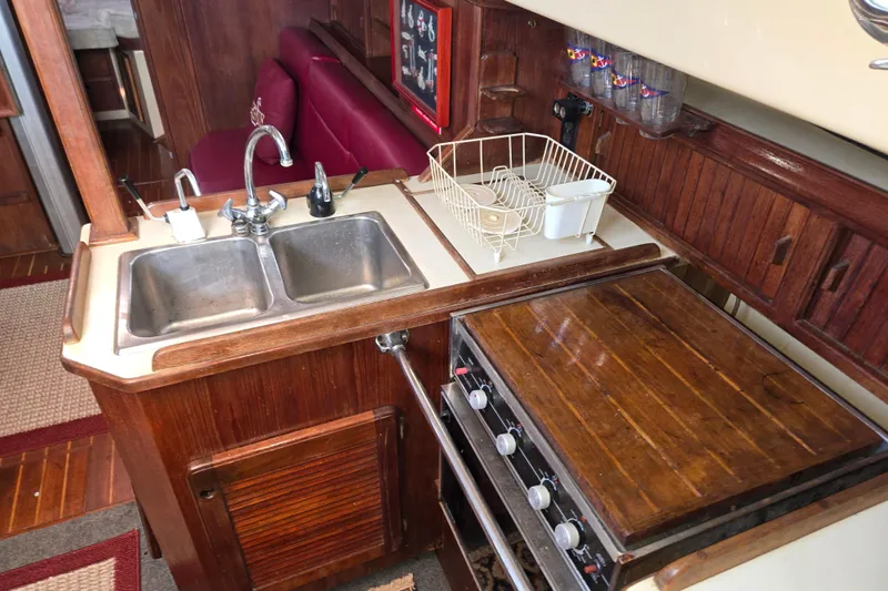 Slide: The Image of 1989 Island Packet 35 yacht kitchen with sink, stove, and wooden cabinetry. - 44