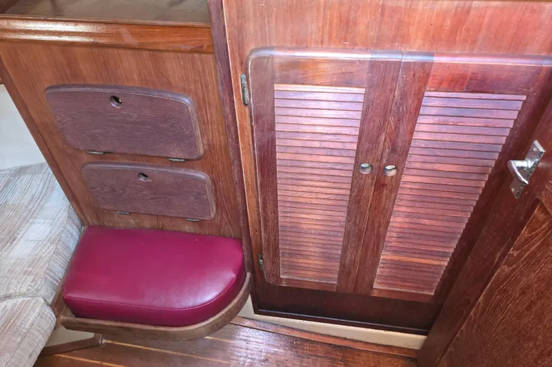 Slide: The Image of Interior of 1989 Island Packet 35 sailboat with wooden cabinetry and red cushioned seat. - 53
