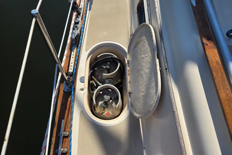 Slide: The Image of Open storage compartment on 1989 Island Packet 35 sailboat deck, revealing propane tanks. - 62