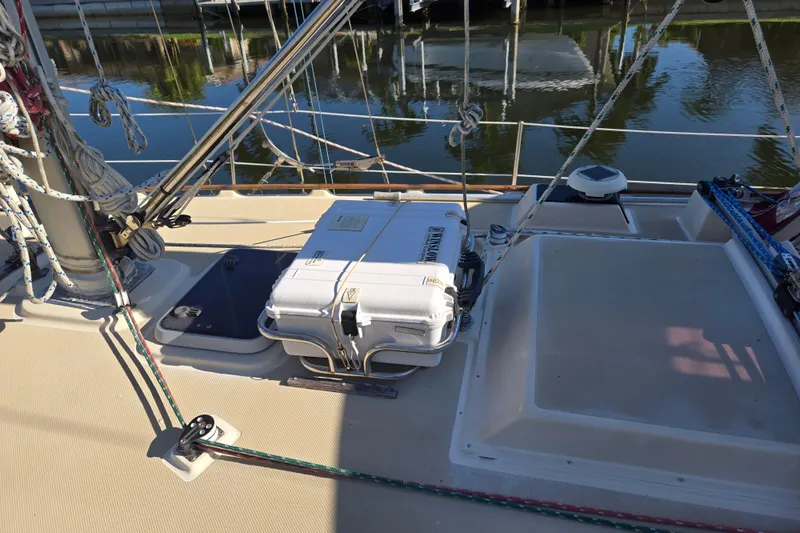 Slide: The Image of 1989 Island Packet 35 sailboat deck with rigging and equipment, docked by calm water. - 63