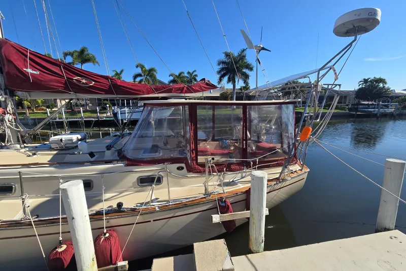 Slide: The Image of 1989 Island Packet 35 sailboat docked, featuring maroon sails and clear cockpit enclosure. - 65