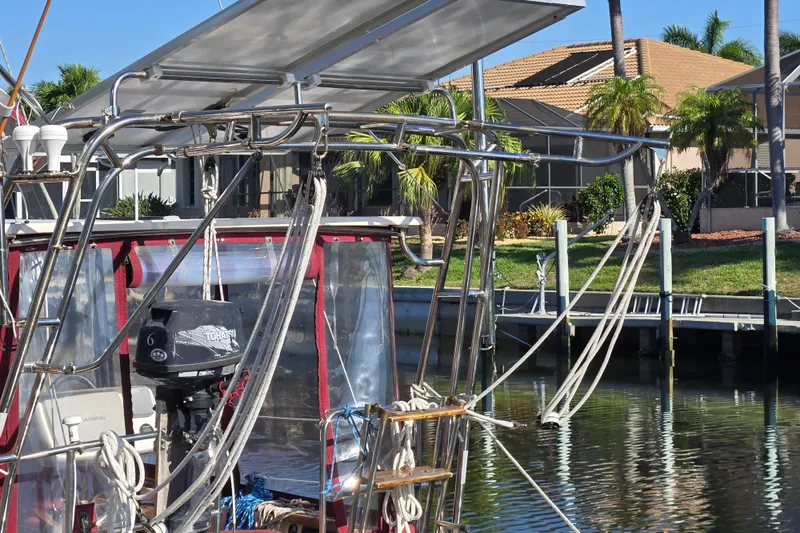 Slide: The Image of 1989 Island Packet 35 sailboat with solar panels and outboard motor, docked near waterfront homes. - 72