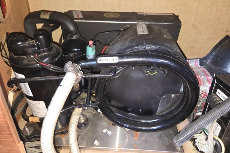 Slide: The Image of 1989 Island Packet 35 engine compartment with visible water-out hose and components. - 79