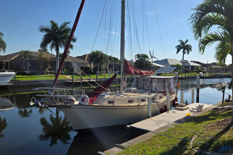Slide: The Image of 1989 Island Packet 35 sailboat docked in a sunny, tropical canal setting. - 80