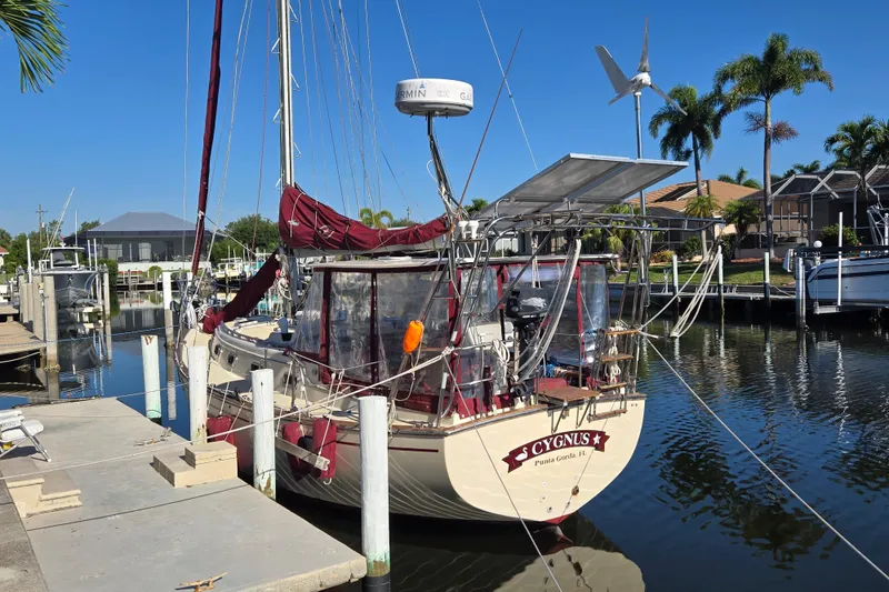 Slide: The Image of 1989 Island Packet 35 sailboat docked in a sunny marina with palm trees. - 82