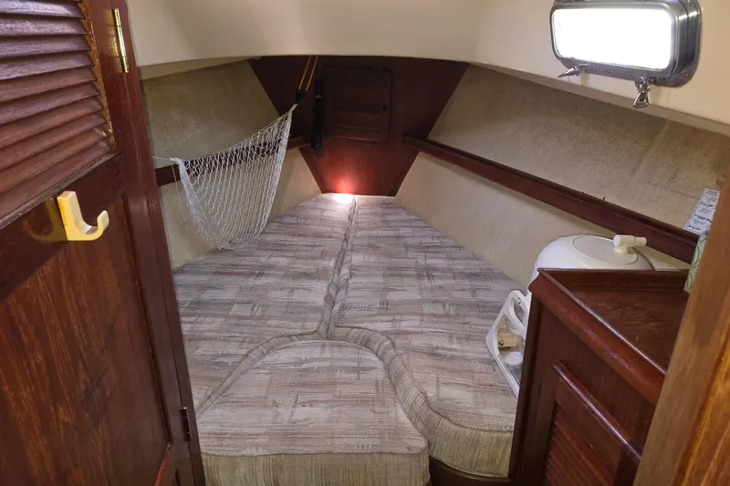 Slide: The Image of Cozy cabin interior of 1989 Island Packet 35 sailboat with cushioned berth and wooden accents. - 9