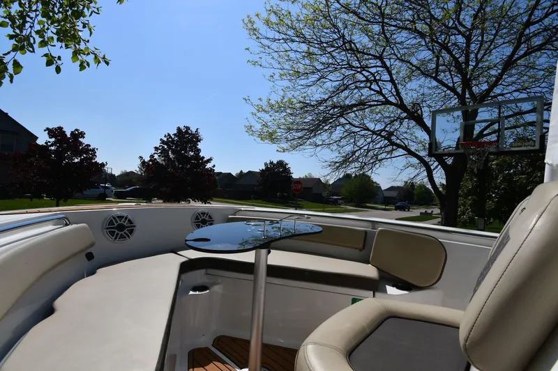Slide: The Image of 2021 Tidewater 210 CC Adventure boat interior with seating and table, set in a suburban neighborhood. - 20