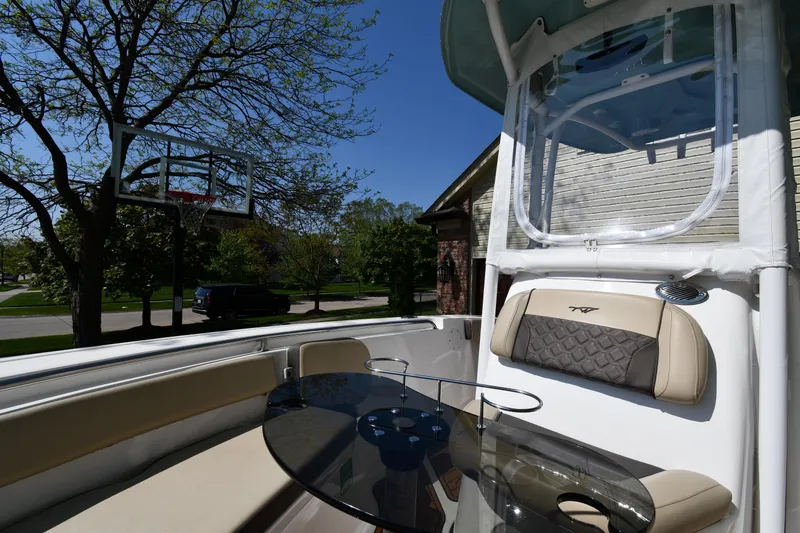 Slide: The Image of 2021 Tidewater 210 CC Adventure boat interior with seating and table, parked near a basketball hoop. - 23