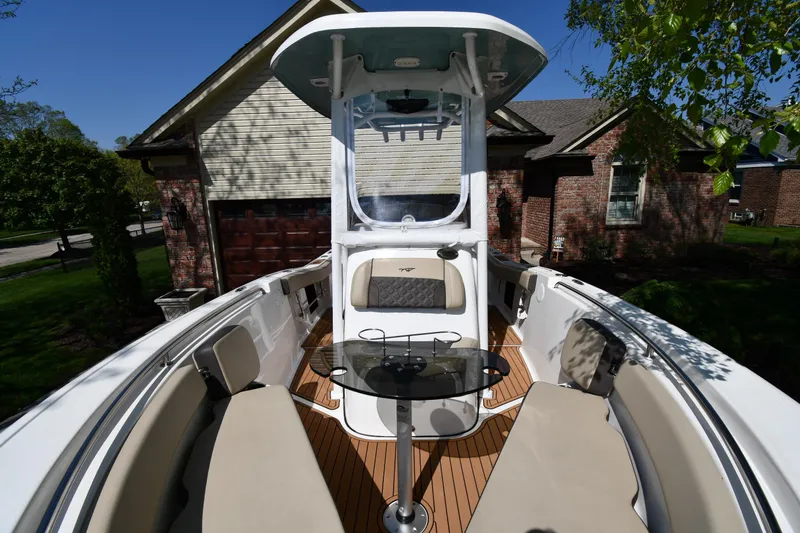 Slide: The Image of 2021 Tidewater 210 CC Adventure boat with seating and table, parked in a residential driveway. - 9