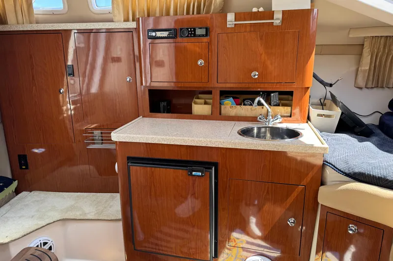 Slide: The Image of 2007 Regal 3060 Window Express boat interior with kitchenette, sink, and wooden cabinetry. - 21