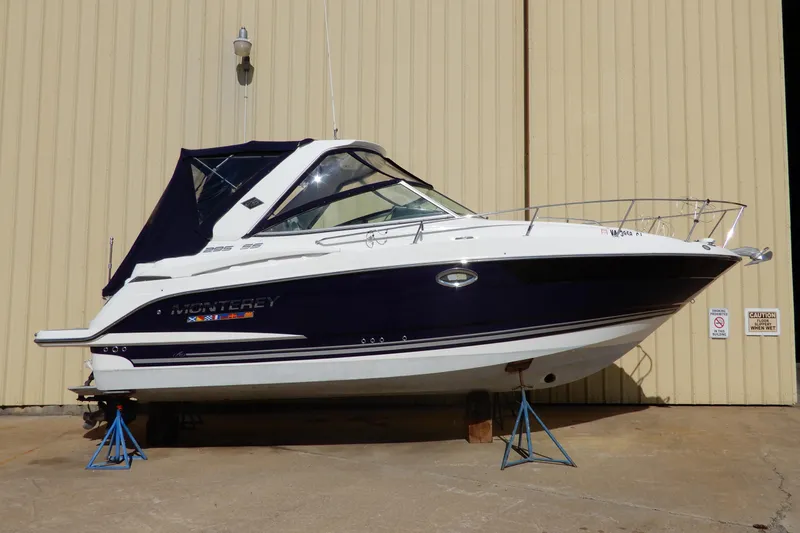 Slide: The Image of 2022 Monterey 295 Sport Yacht on stands, displayed outdoors against a beige wall. - 1