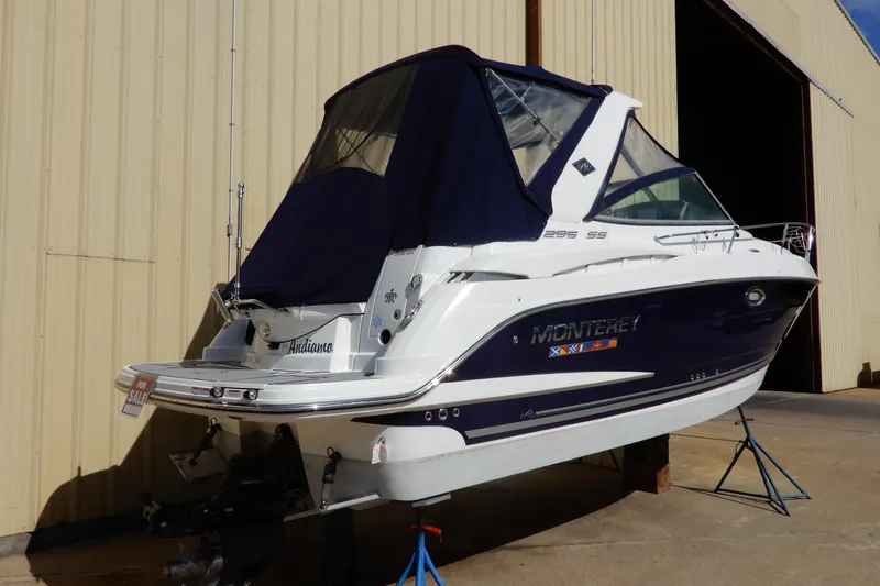 Slide: The Image of 2022 Monterey 295 Sport Yacht for sale, docked near a large building. - 2