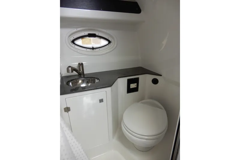 Slide: The Image of 2022 Monterey 295 Sport Yacht bathroom with sink, toilet, and porthole window. - 46